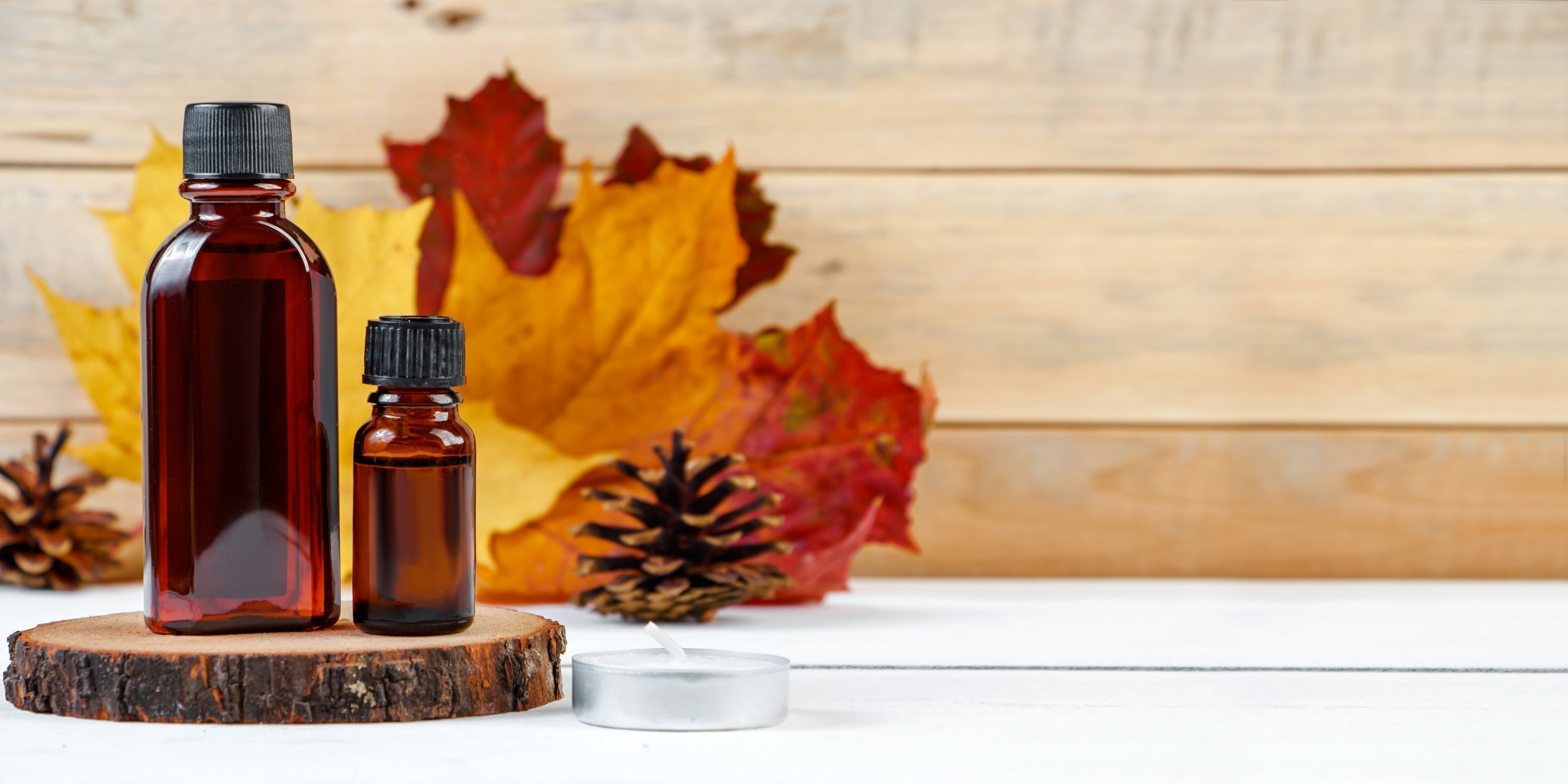 Essential oil bottle for aromatherapy. Autumn skin care concept. Cosmetic serum on a wooden pedestal.