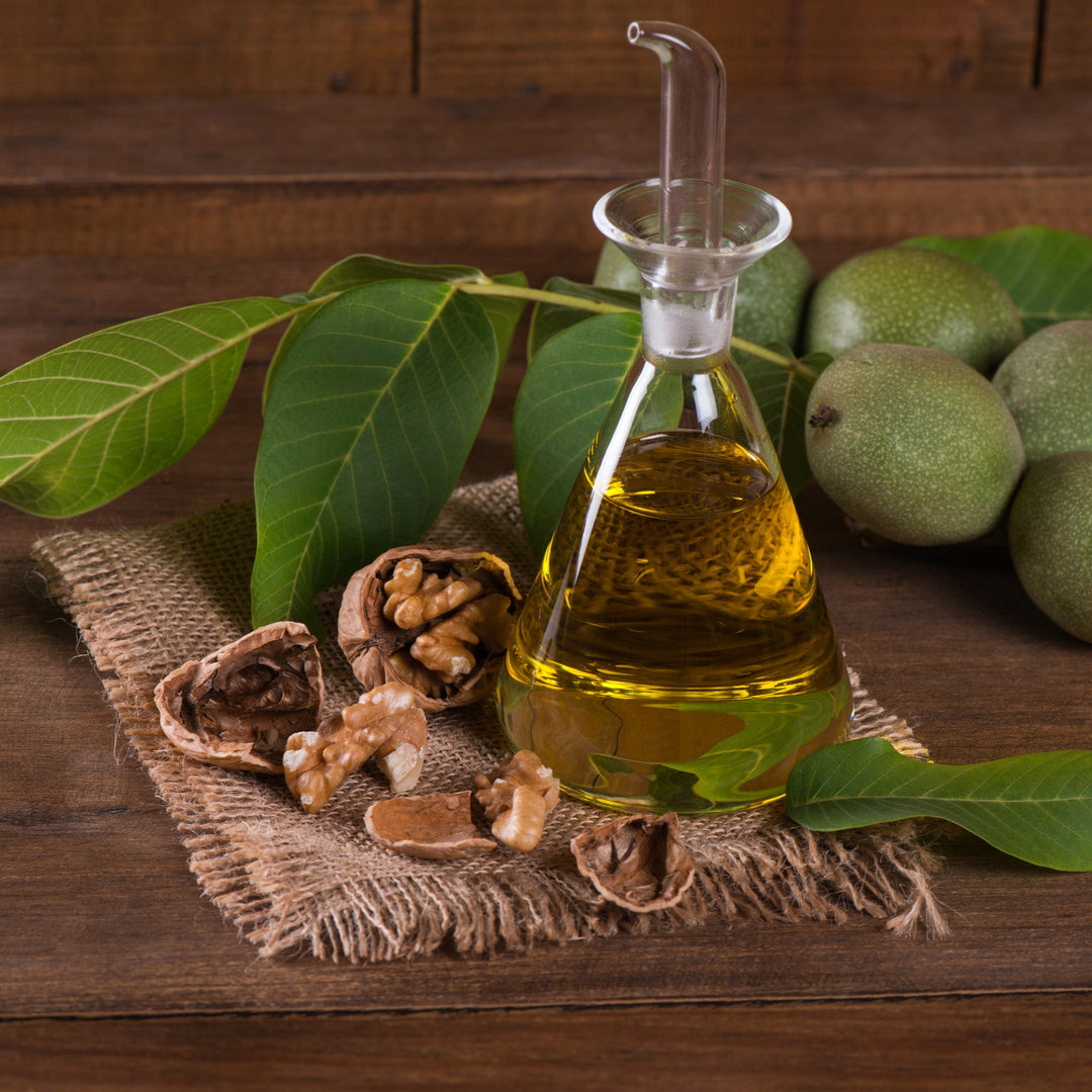 Dried and green walnuts with leaves and oil on wooden table