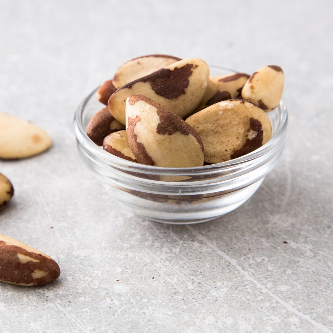 Organic Brazil Nuts in glass jar on neutral background