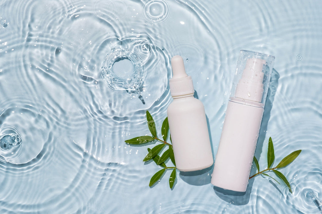 White cosmetic bottles on water drenched background