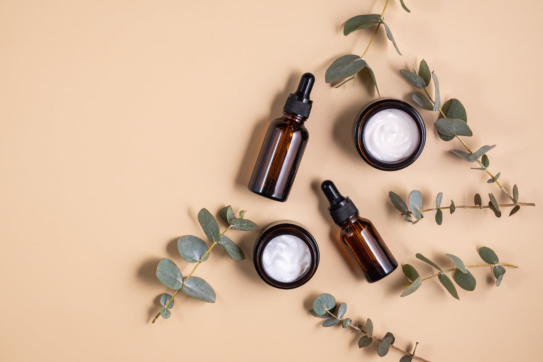 Brown glass bottles and eucalyptus branches on beige background.