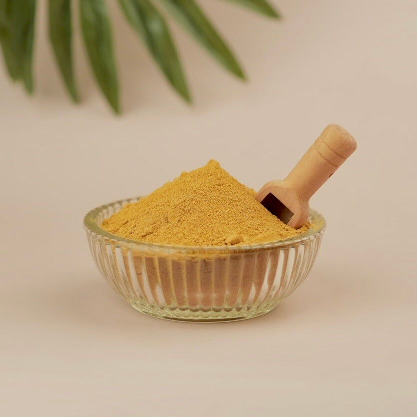Glass bowl filled with yellow powder on a beige background