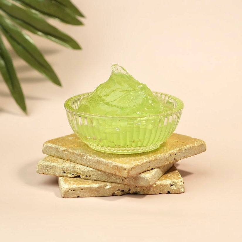 Clear glass bowl with green gel on three tile, beige background with a leaf