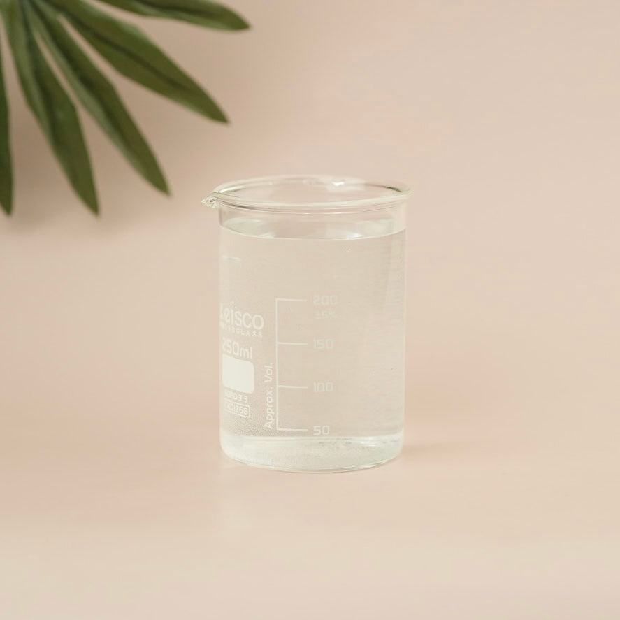 Clear glass beaker with measurement markings on a beige background