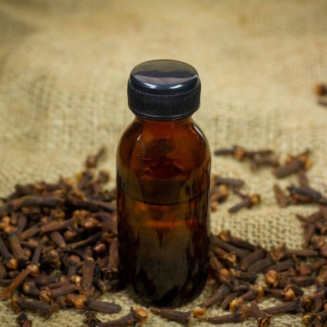 Brown bottle with black cap on a background of dried cloves
