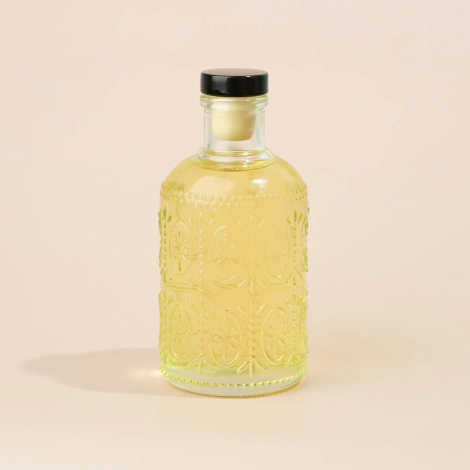 Golden oil in a decorative glass bottle with tan backround