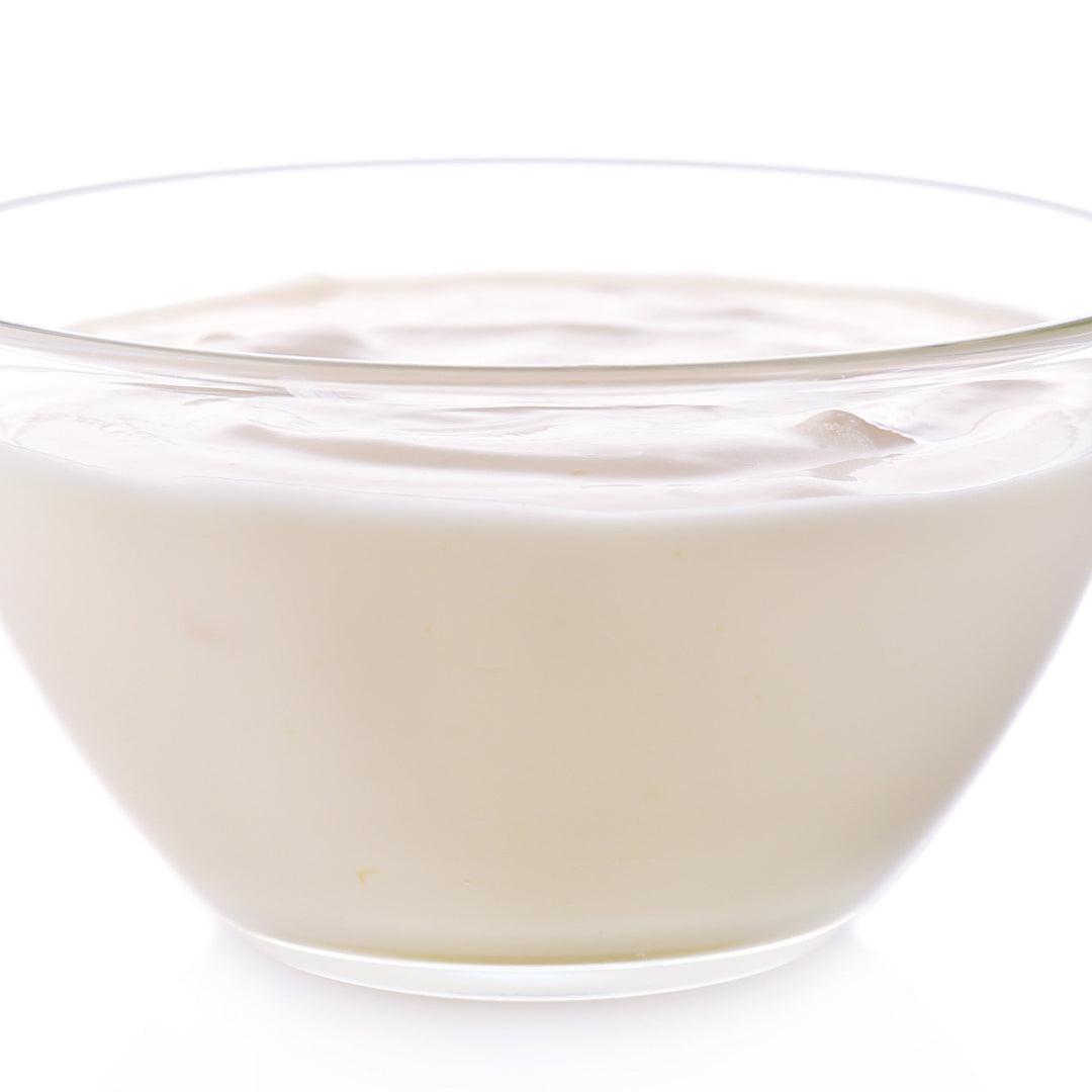 A clear glass bowl filled with plain white ceramide liquid, placed on a white background.