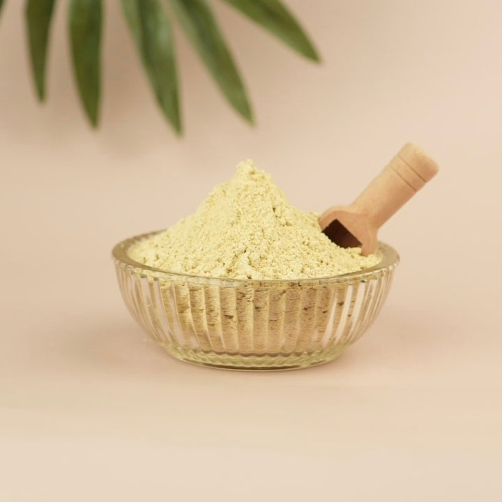 Glass bowl filled with light-colored powder on a beige background