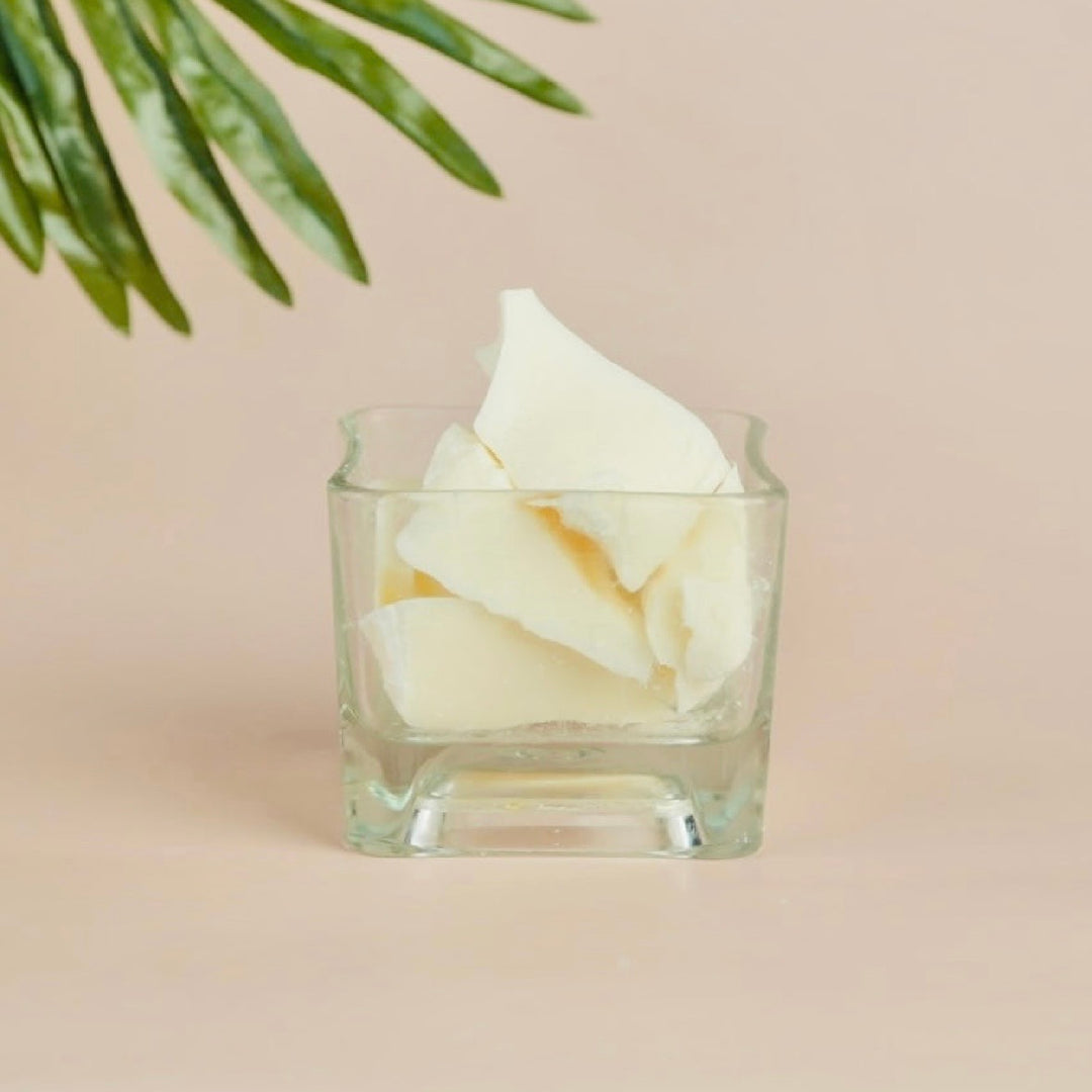 Glass vase filled with cocoa butter with white flowers on a beige background