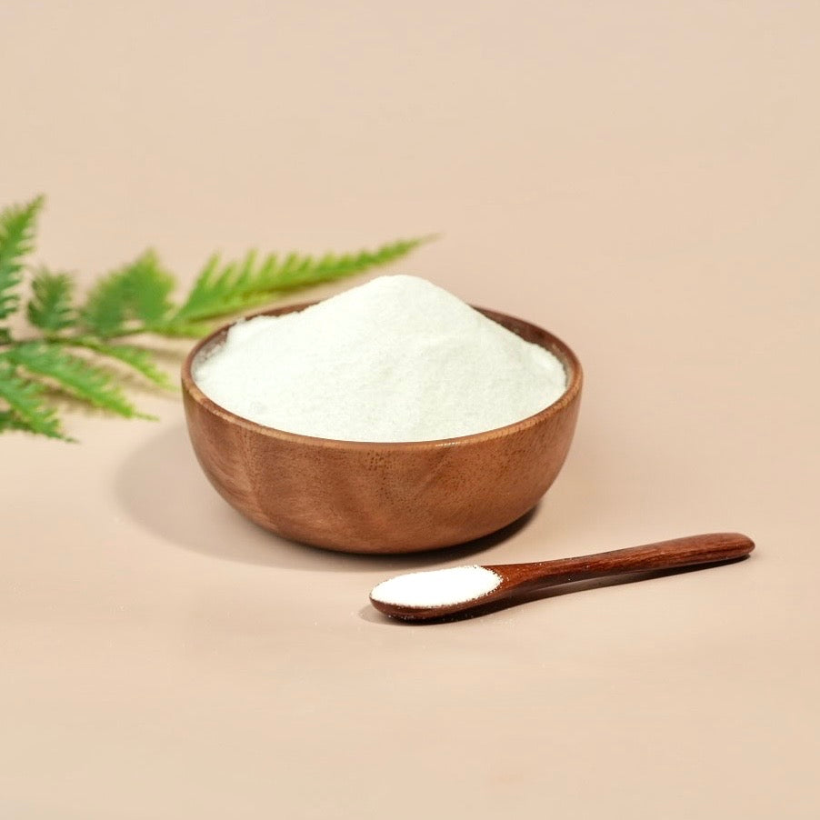 Wooden bowl and spoon with white powder on a beige background