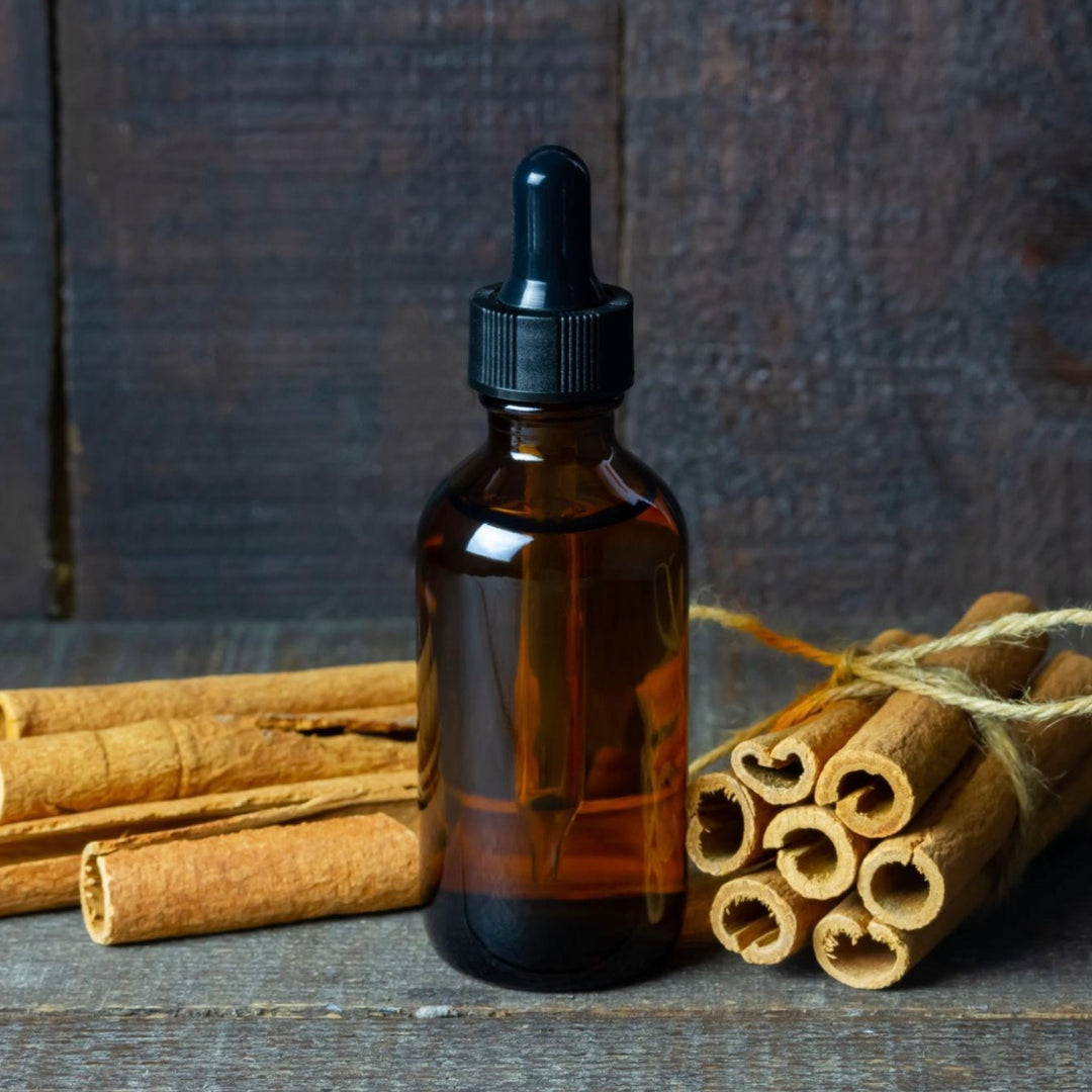 Brown glass dropper bottle with cinnamon sticks on a wooden surface
