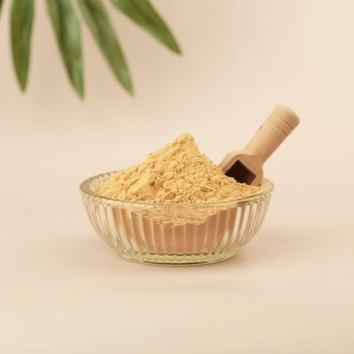 Tan background, glass bowl , tan powder, wooden scoop