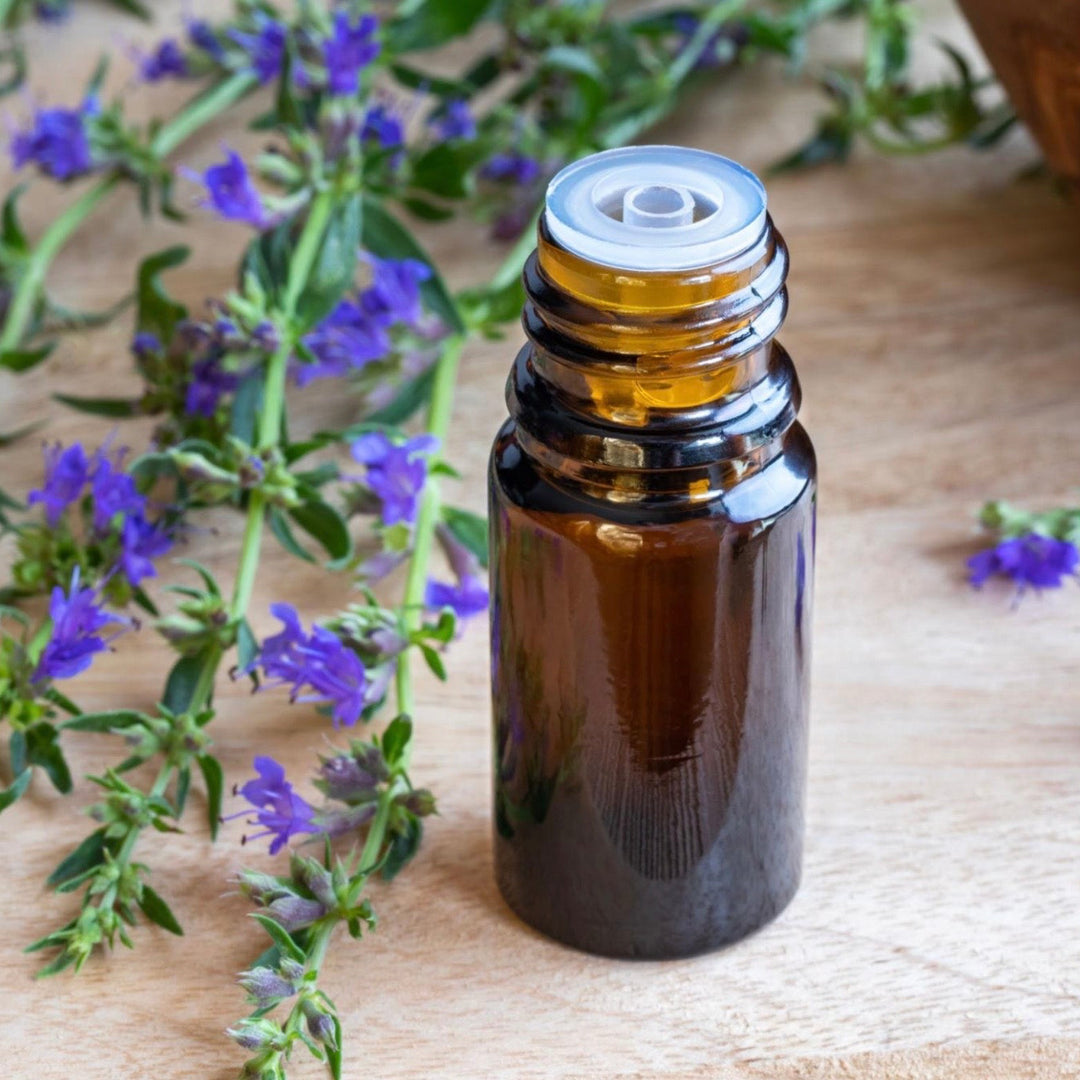 Brown glass essential oil bottle with purple flowers on a wooden surface