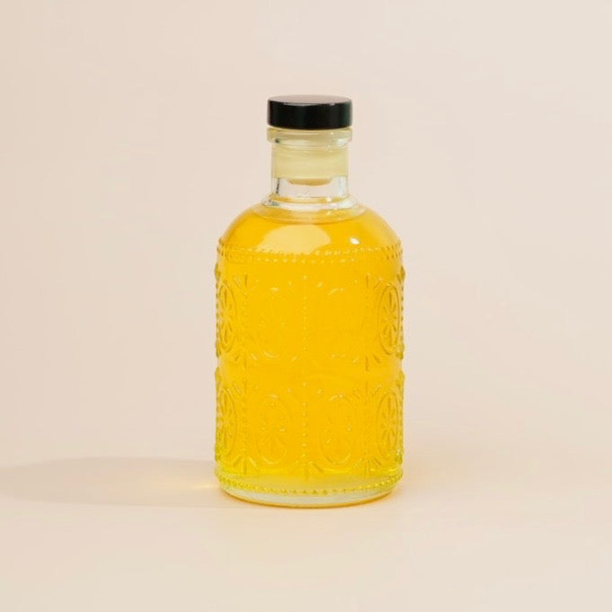 Bottle of yellow liquid with a black cap on a beige background
