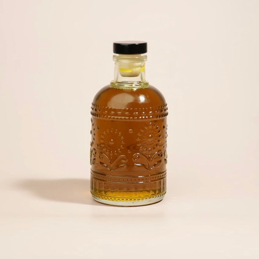 Bottle of amber liquid with a black cap on a beige background