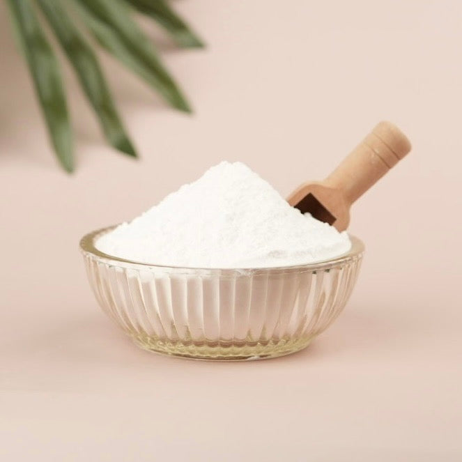 Clear glass bowl filled with white powder on a light pink background