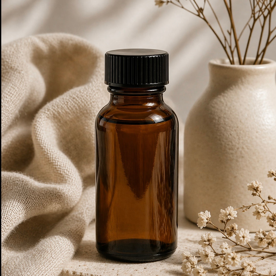 Brown glass bottle with black cap on a neutral background with flowers and fabric.