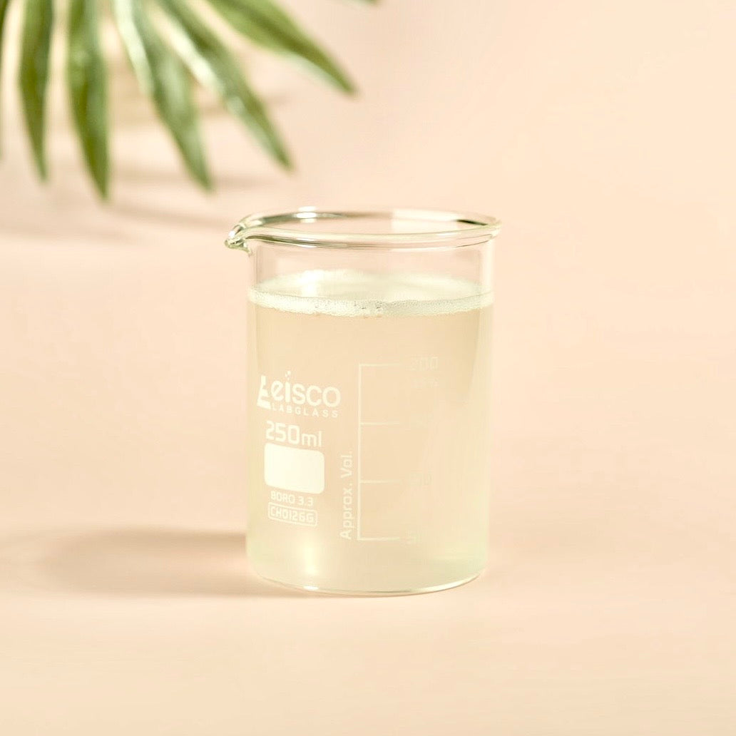 Clear glass beaker with liquid on a beige background
