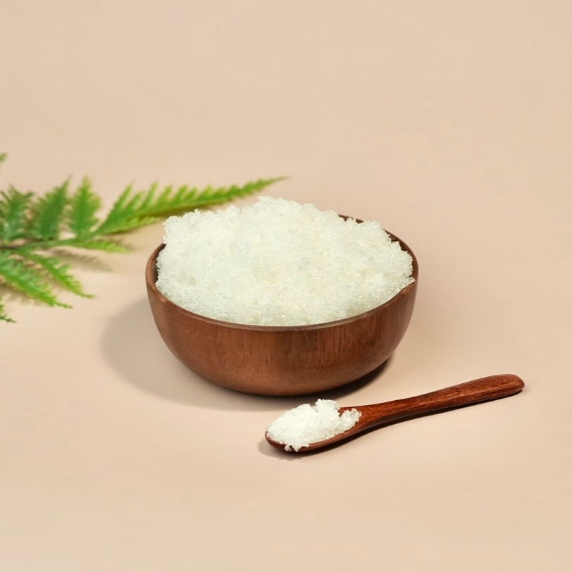 Wooden bowl and spoon filled with white salt on a beige background