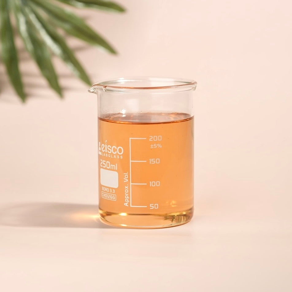 Beaker with orange liquid on a beige background