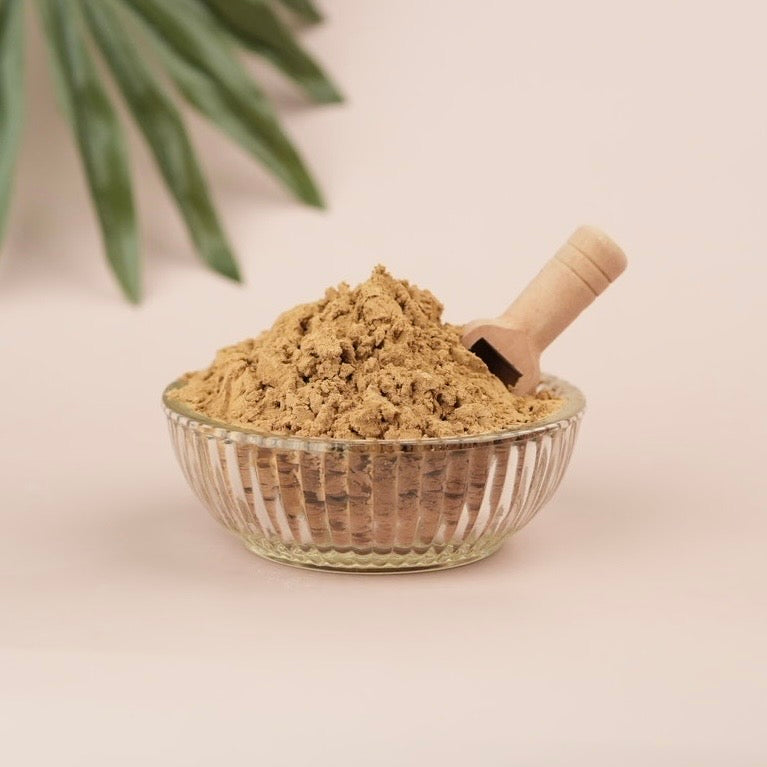 Glass bowl filled with brown powder on a light background