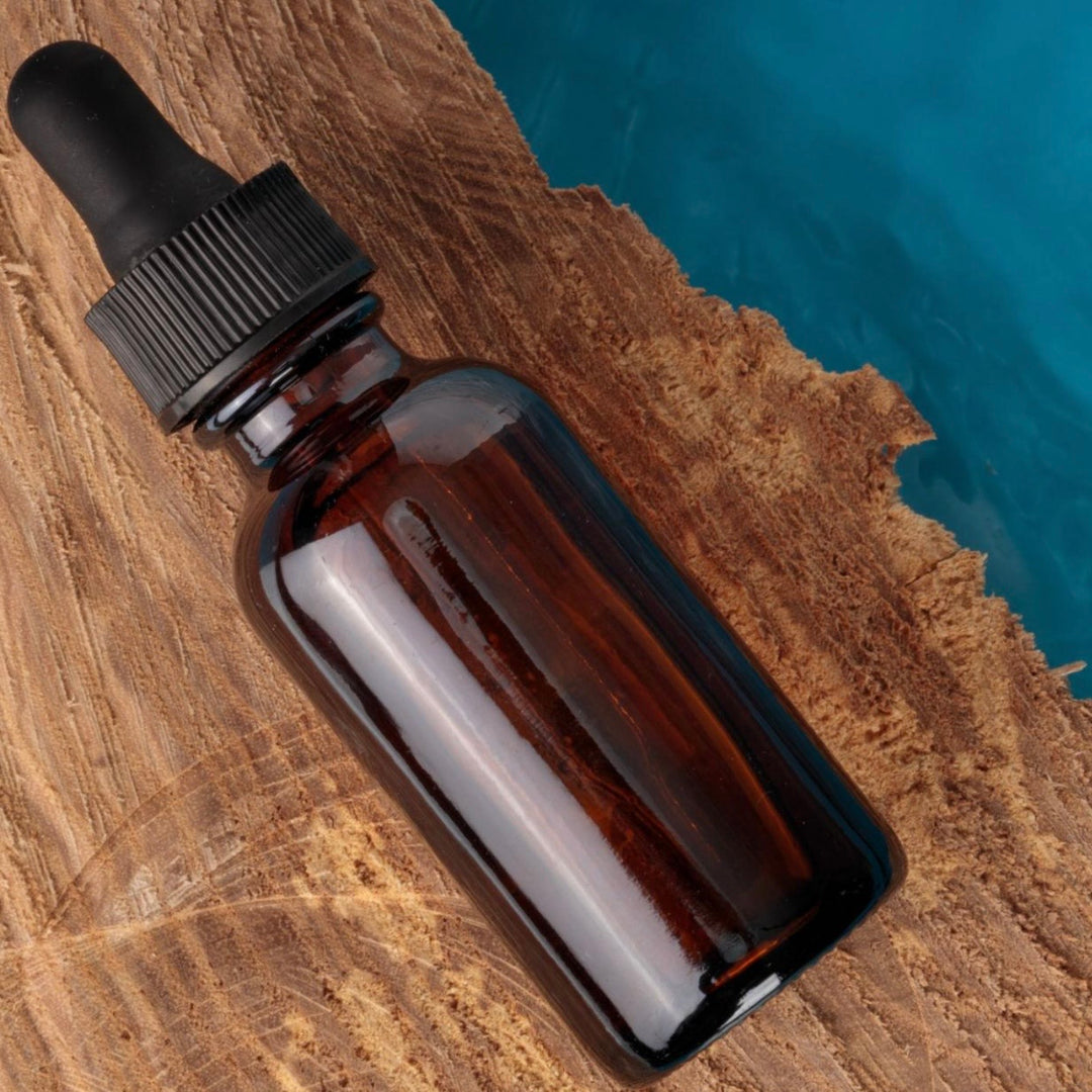 Brown glass dropper bottle on a wooden surface with a blurred blue background