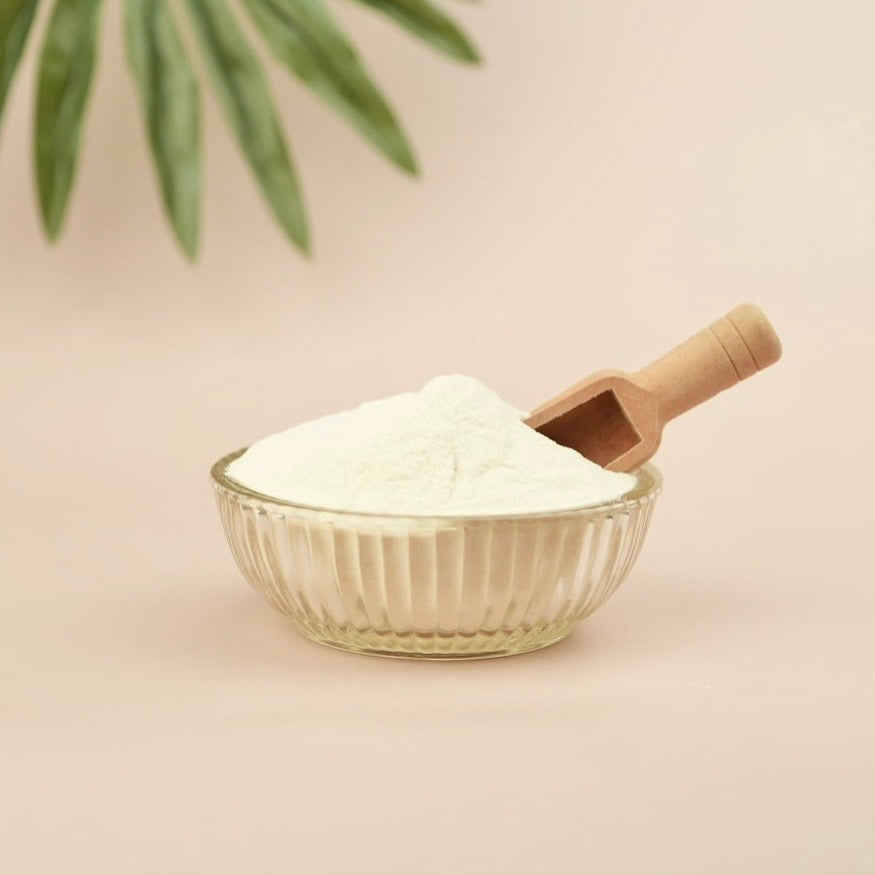 Tan background, glass bowl, wooden scoop, beige powder