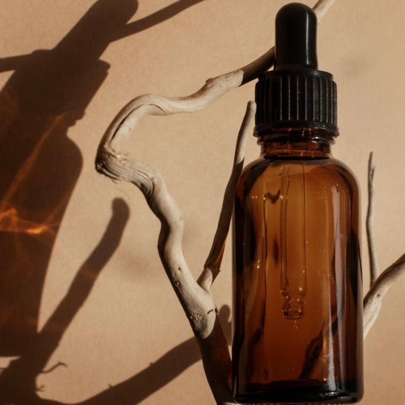 Brown glass dropper bottle on a beige background with shadows