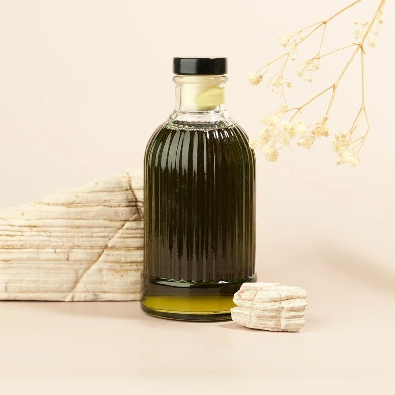 Tan background, white rocks and a decorative bottle with infused green oil
