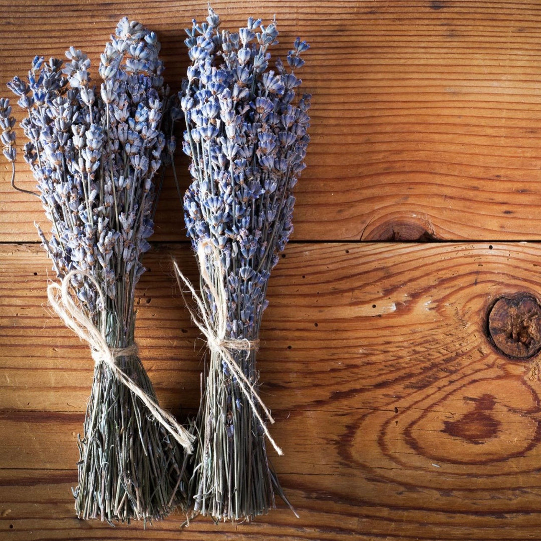 Two bundles of dried lavender on a wooden surface