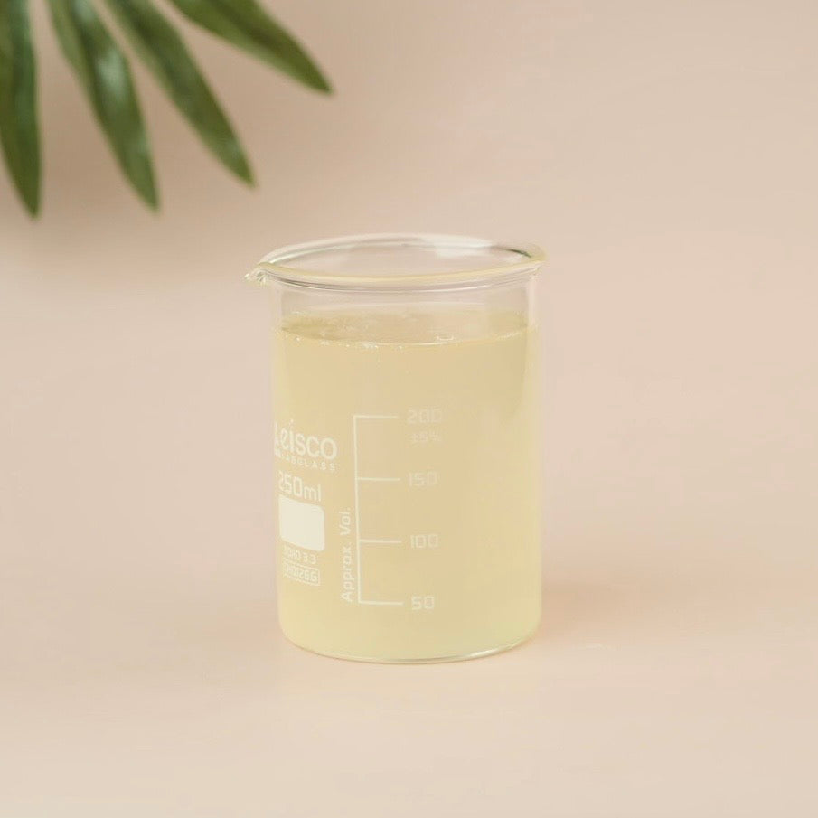 Clear beaker with green liquid on a beige background