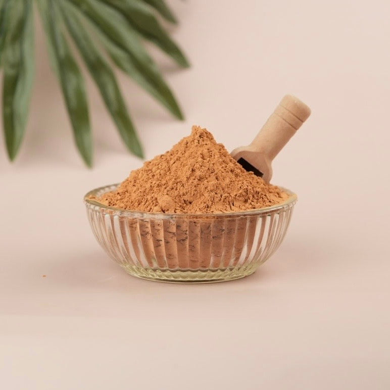 Glass bowl filled with brown powder on a light background