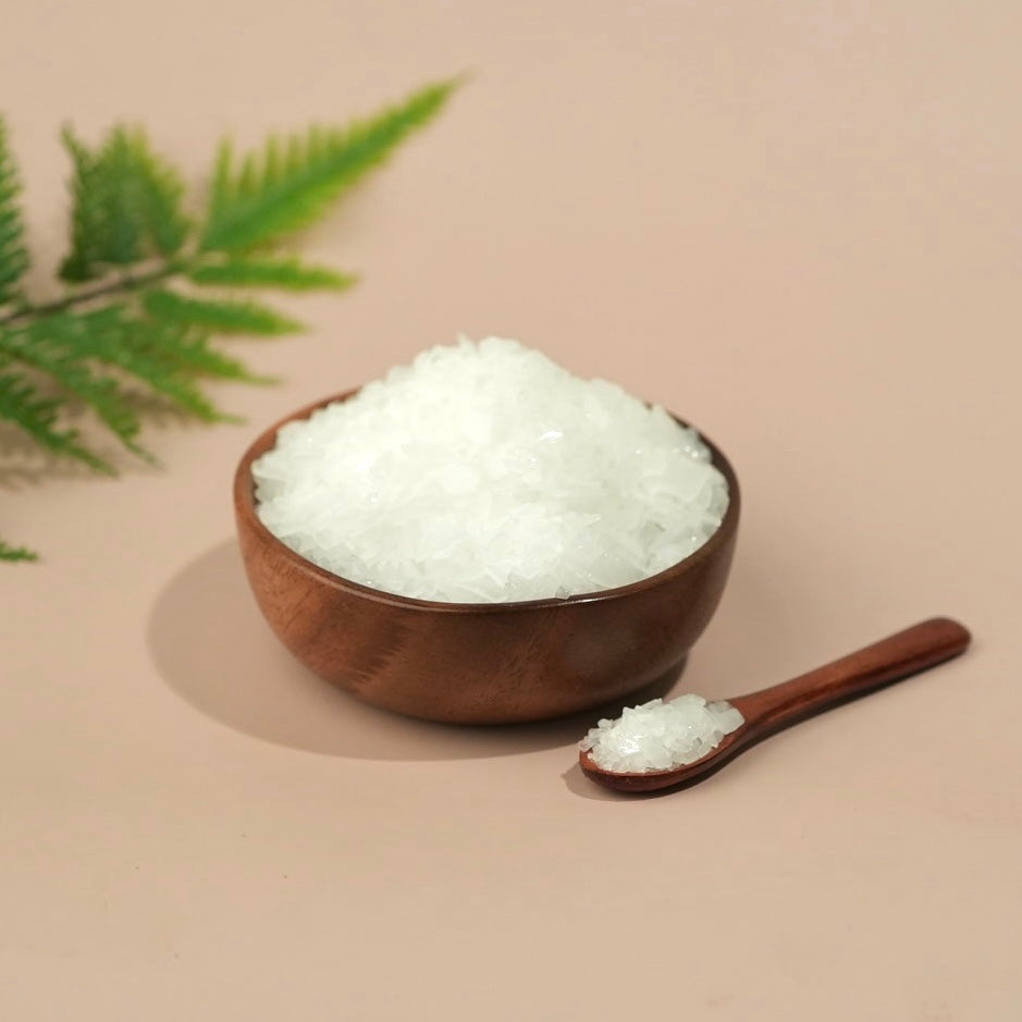 Wooden bowl and spoon filled with white granulated product on a beige background