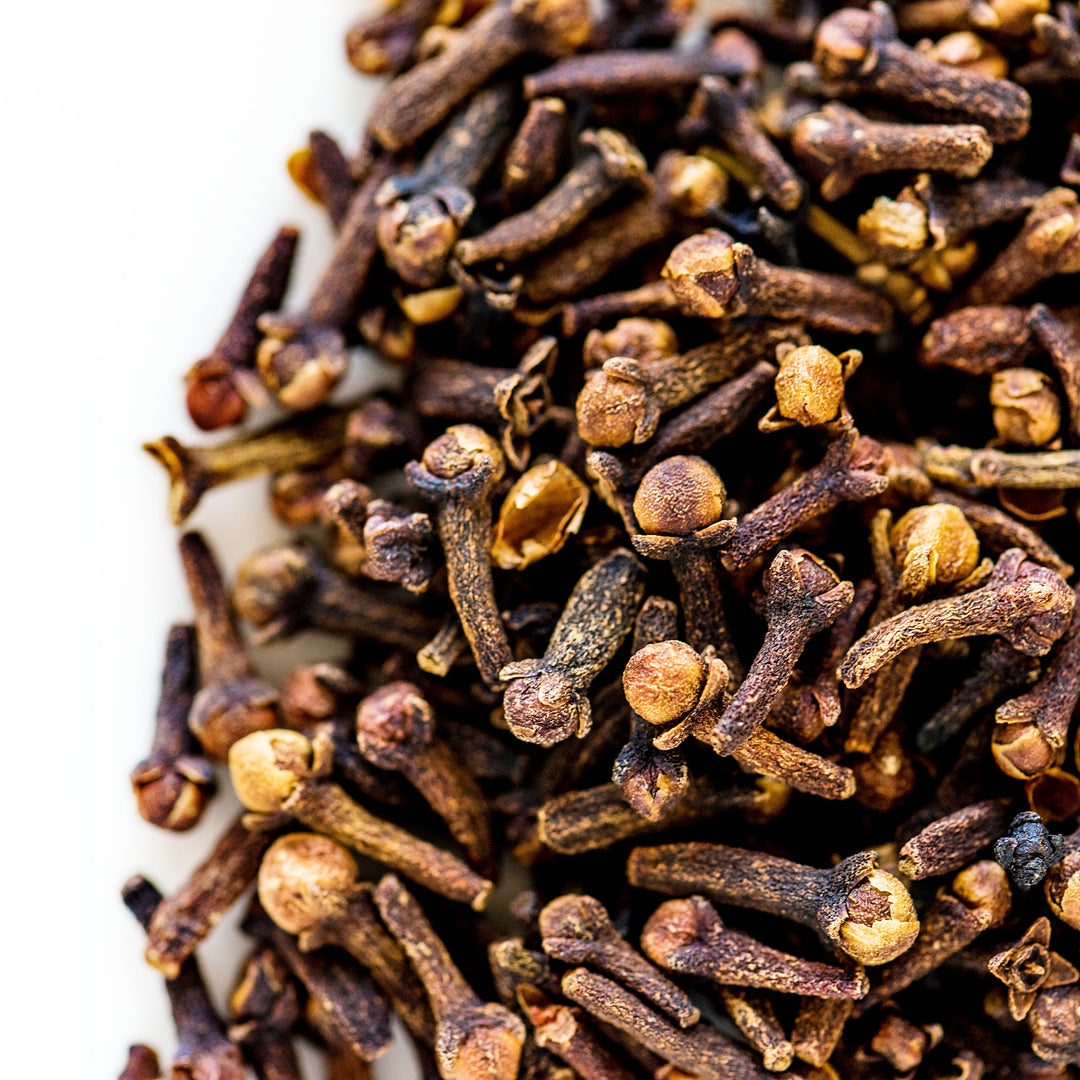 A close-up of whole clove buds, with a woodsy appearance, used to produce essential oil.