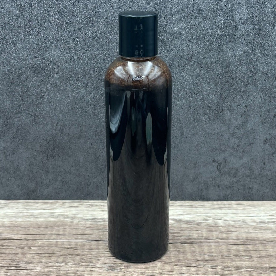 Black bottle with a dark cap on a wooden surface and gray background